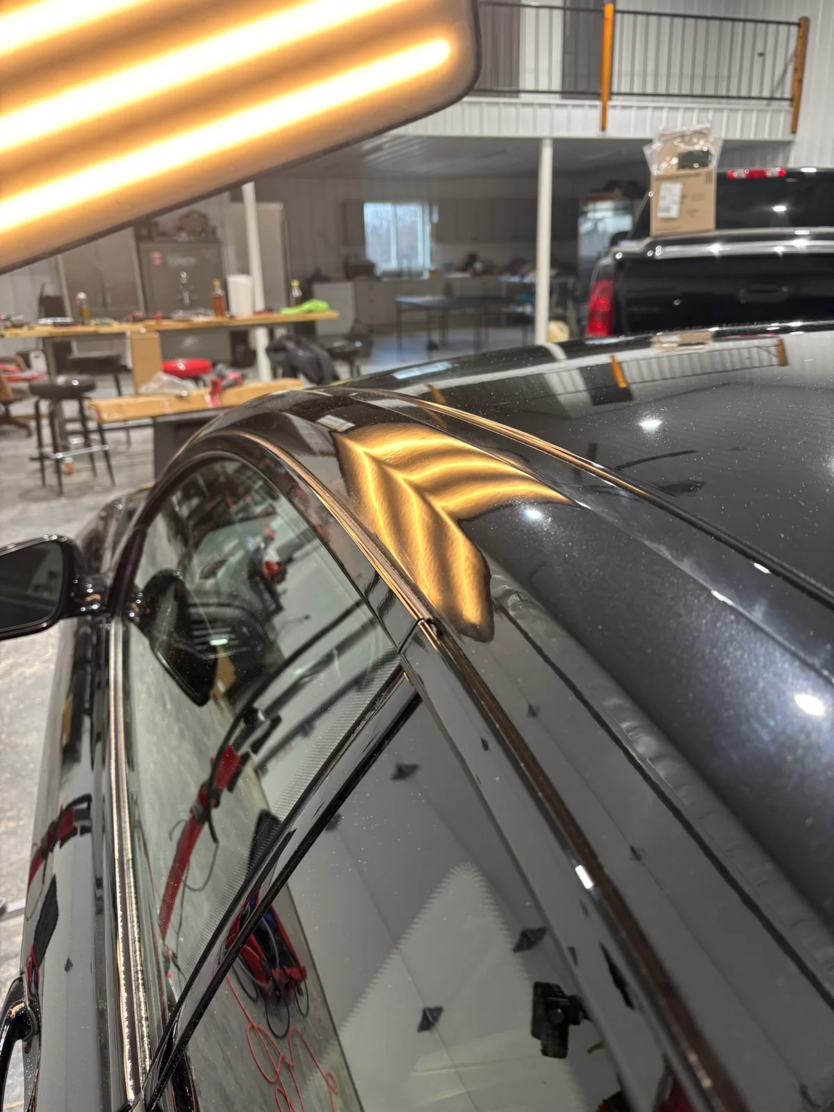Paintless dent repair rod in action behind a vehicle panel during a repair pass