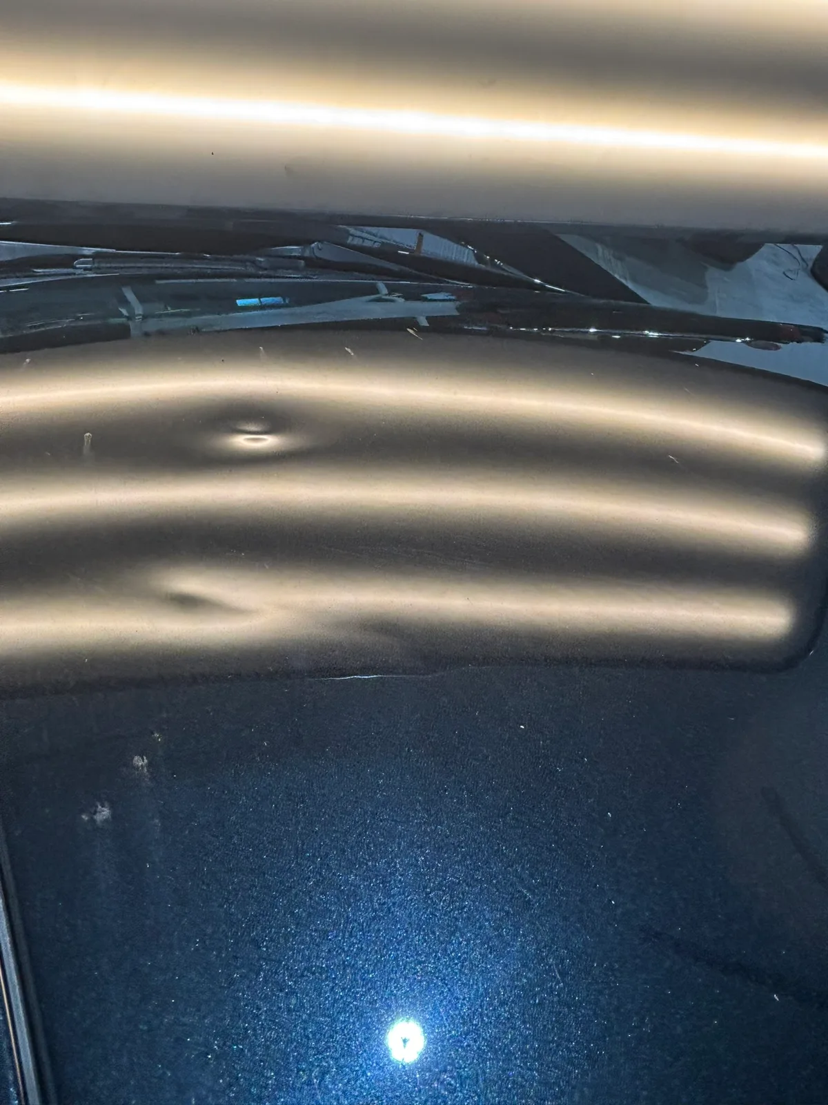 Close-up view of hail dents on a vehicle roof with LED stripe reflections