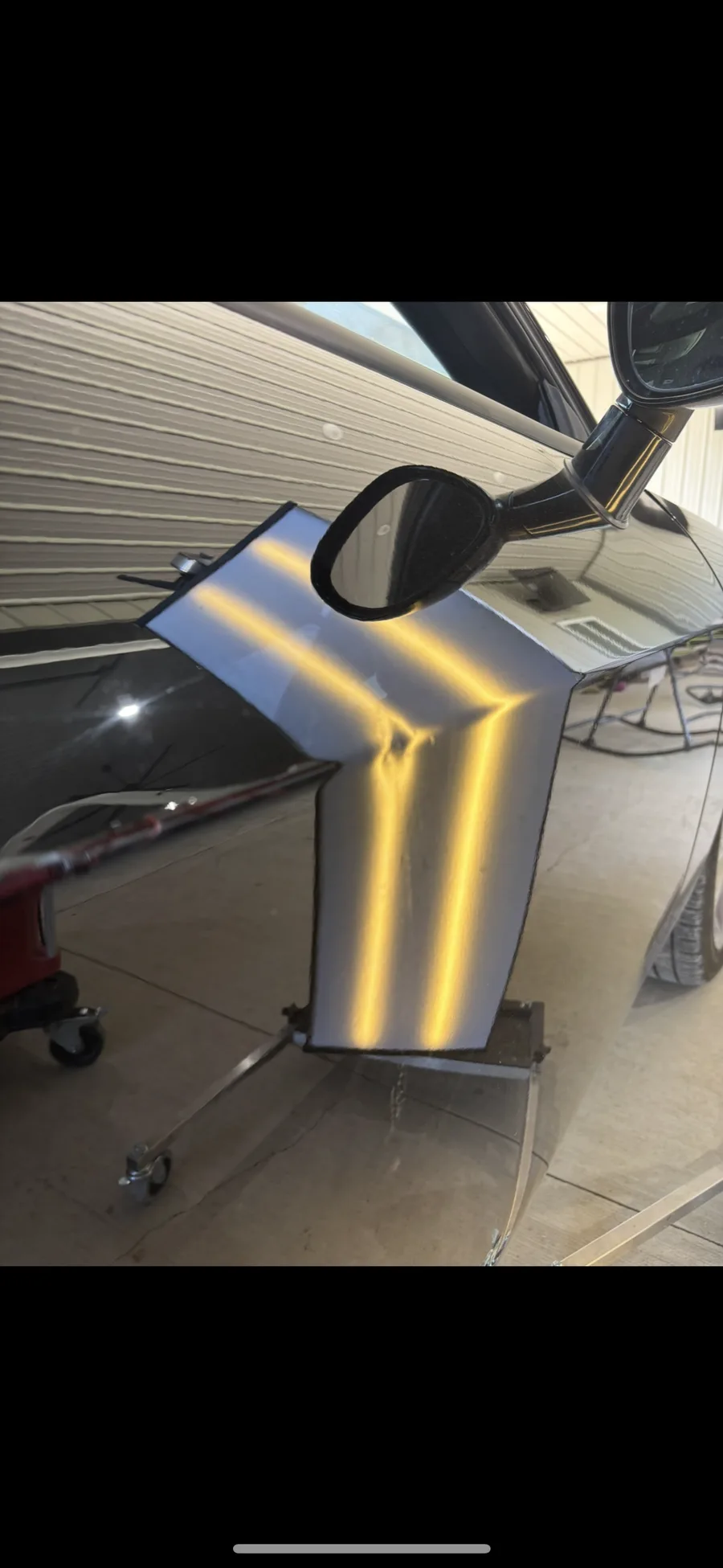 Detached vehicle panel on a stand under LED line-board inspection in the Hail Solutions shop