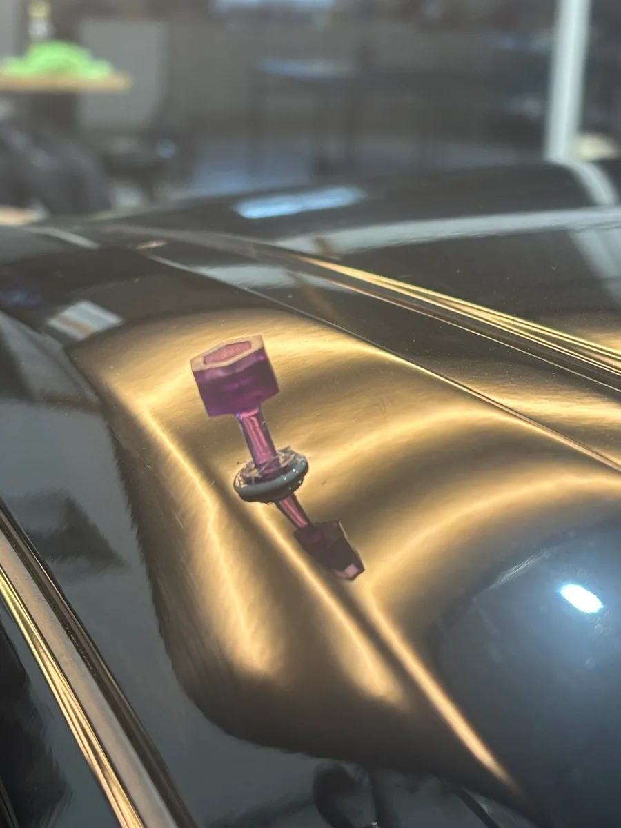 Purple glue-pull tab mid-repair on an aluminum body panel