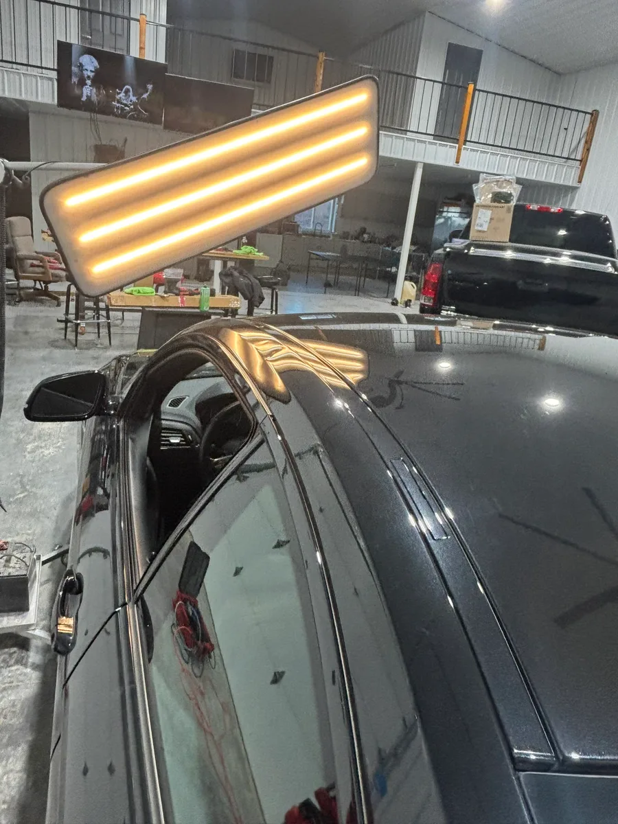 LED line board casting stripe reflections across a vehicle panel revealing hidden hail dents