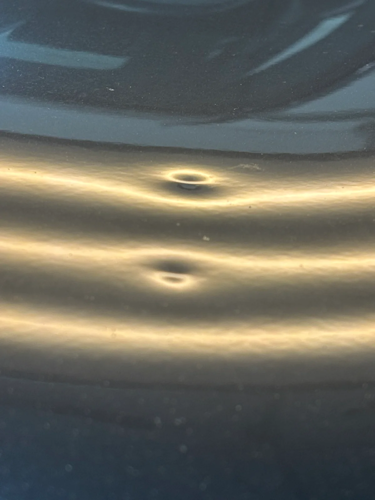 Hail-damaged hood in the Hail Solutions Olathe shop under LED line-board inspection